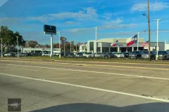 Lincoln dealership with Texas flags near highway