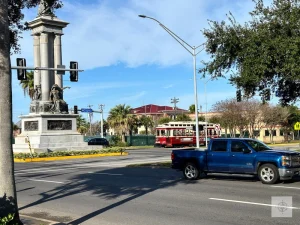 Texas Heroes Monument in Galveston with historic trolley passing by