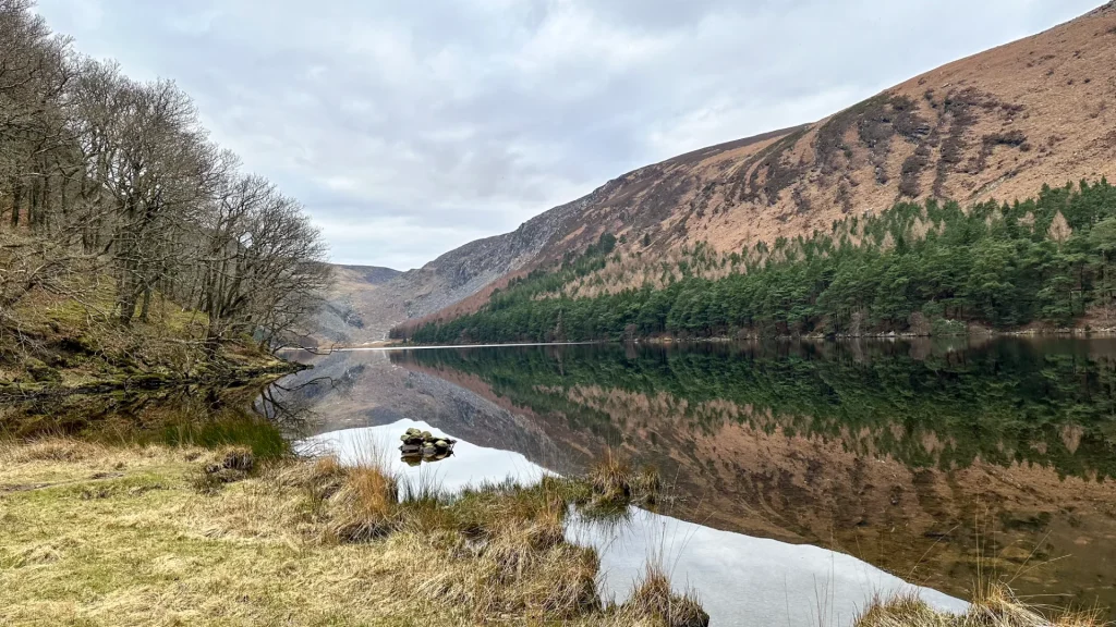 Upper Lake in Glendalough with mountain reflection on calm water