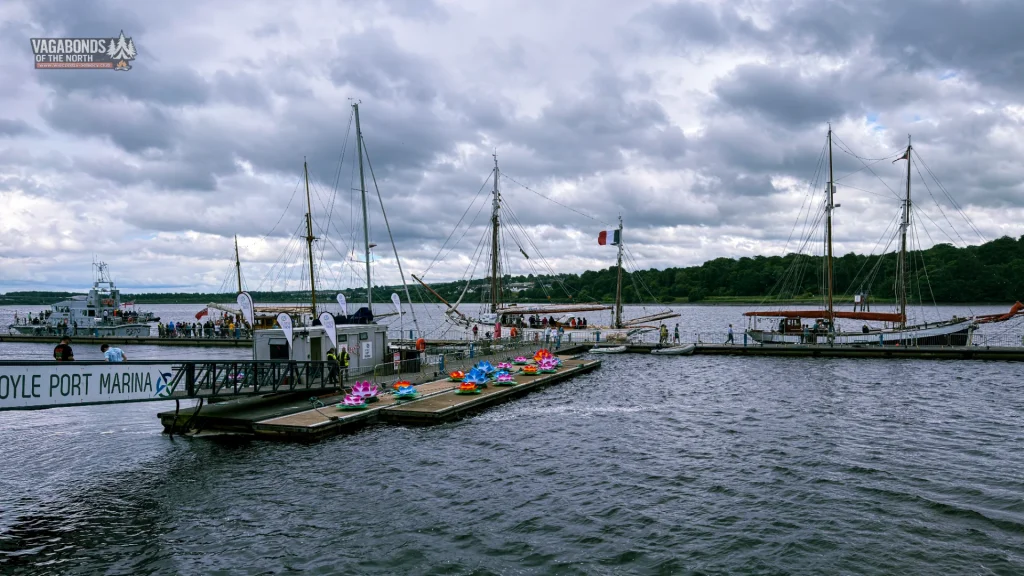 Żaglowce zacumowane podczas Foyle Maritime Festival w Derry, kolorowe dekoracje na pomoście i rzeka Foyle.